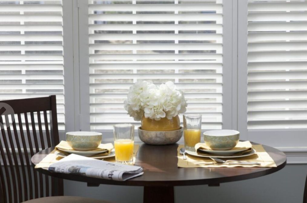 A cozy dining table set for breakfast with flowers and orange juice.