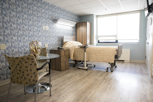 A well-lit and clean hospital patient room featuring a bed, chair, and modern furnishings.
