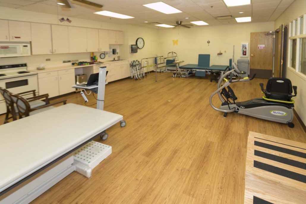 A spacious physical therapy room equipped with various exercise machines and therapy beds.
