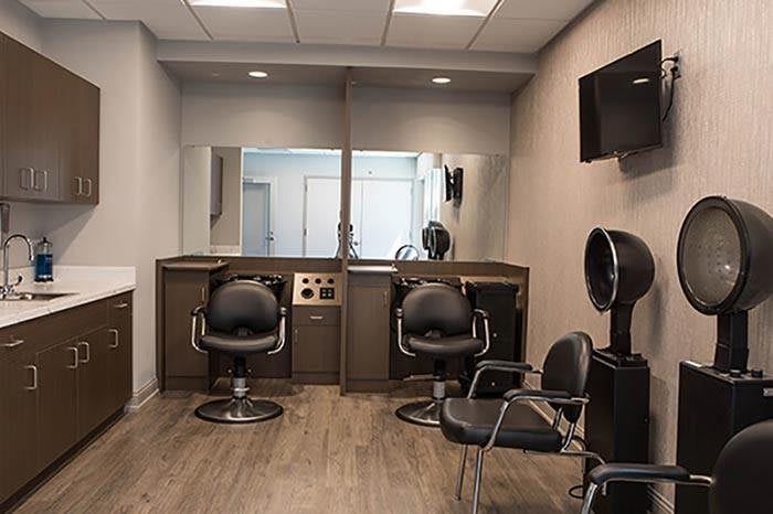 A modern hair salon with styling stations and chairs, featuring mirrors and a clean interior design.