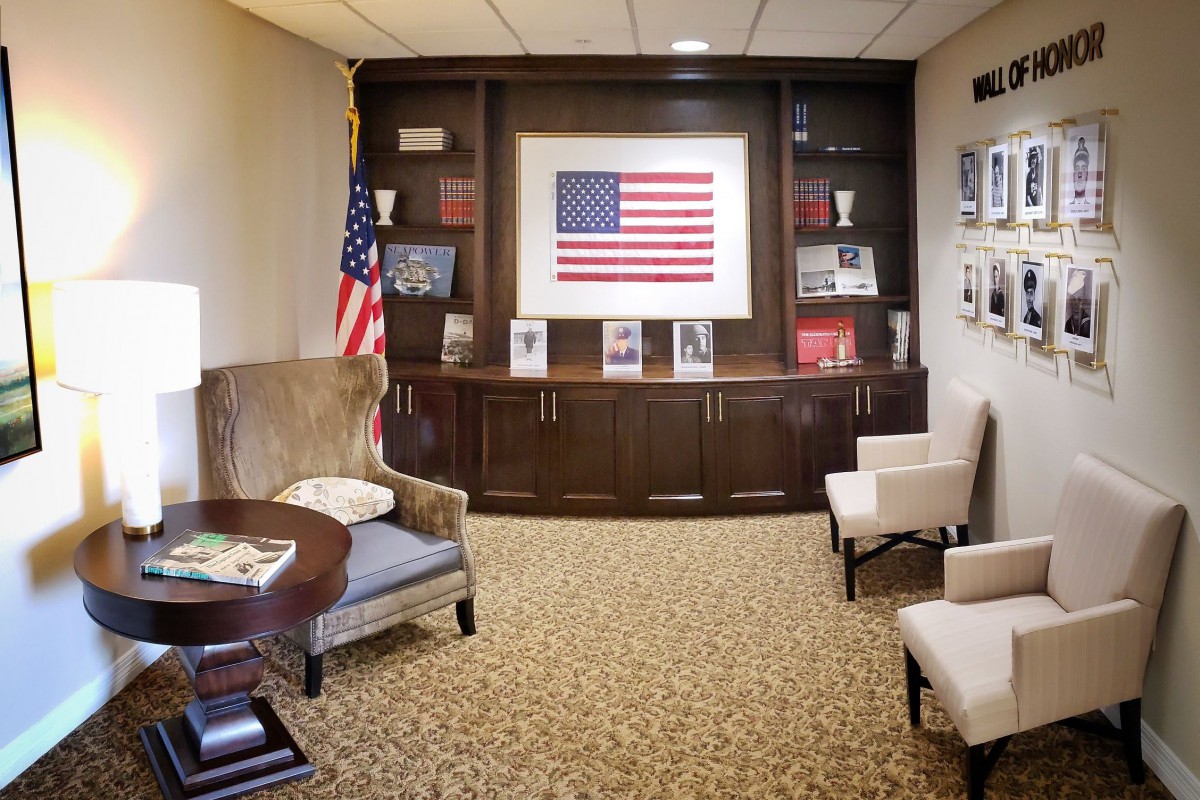 An office seating area with an American flag display, bookshelves, and chairs.