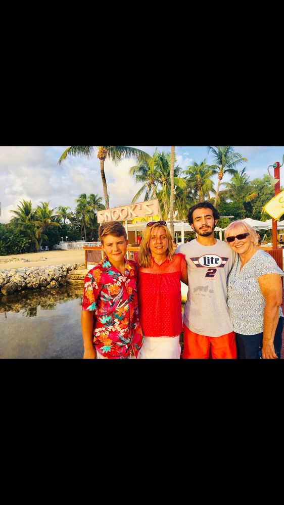 A family enjoying their time together at a tropical beach destination, surrounded by palm trees and sunlight.