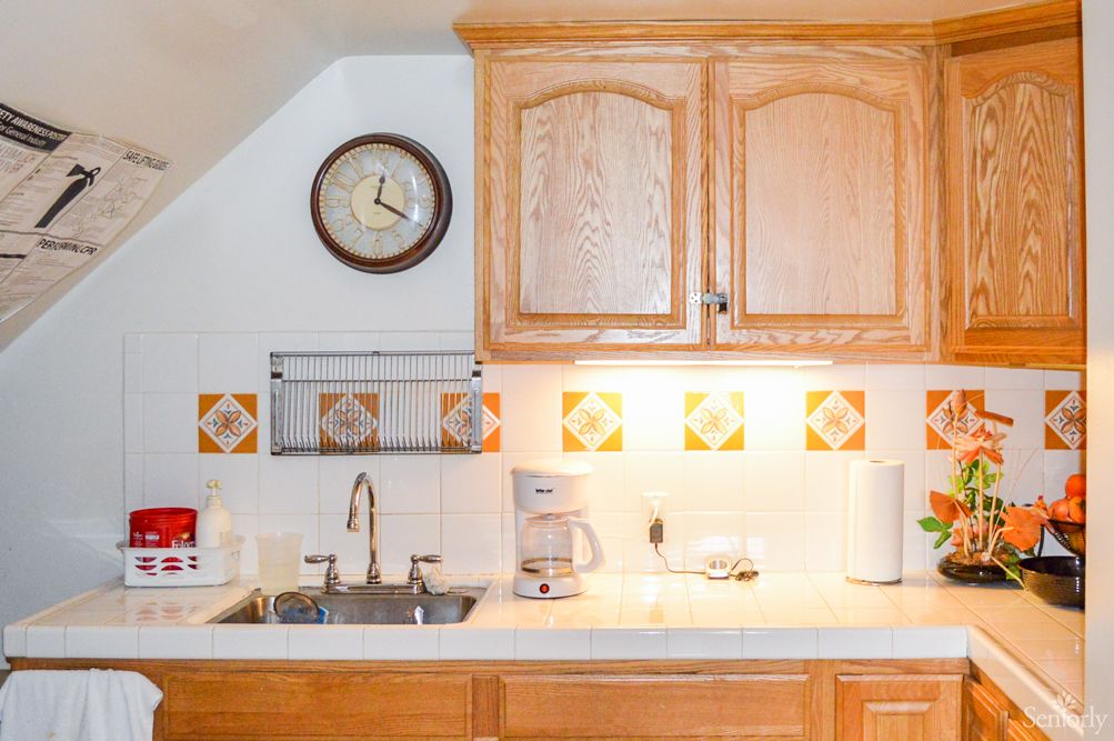 A cozy kitchen with wooden cabinets, a sink, and a clock on the wall.