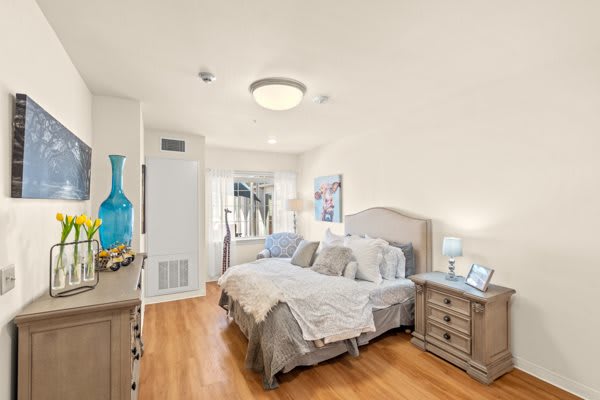 A cozy bedroom with a neatly made bed, nightstands, and soft lighting.