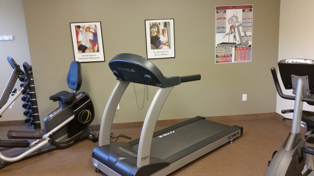 A treadmill in a fitness room with motivational posters on the wall.