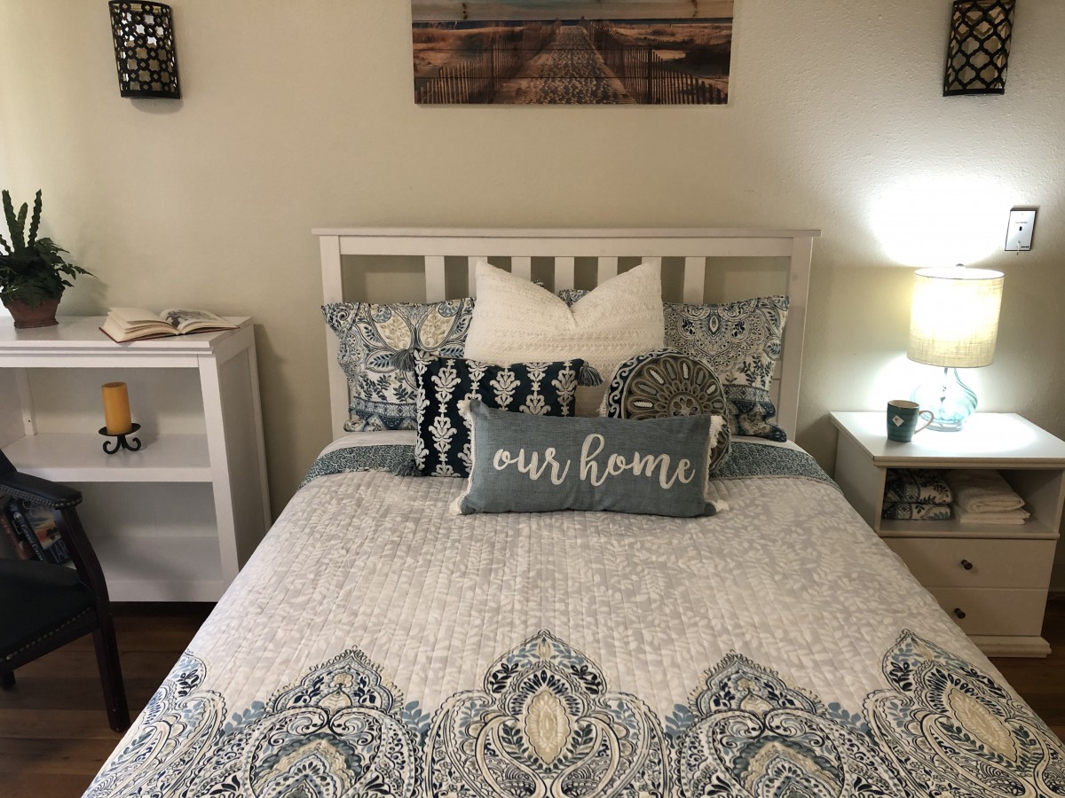 A cozy and well-decorated bedroom featuring a neatly made bed with patterned bedding and decorative throw pillows.