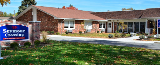 A charming single-story brick house surrounded by a well-kept lawn and autumn foliage.