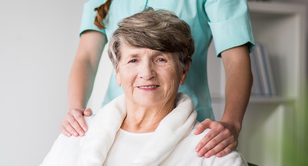 An elderly woman receiving support from a caregiver.