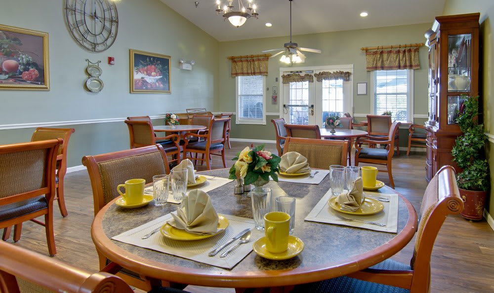 A dining room with tables set for a meal, featuring yellow crockery and neatly arranged napkins.