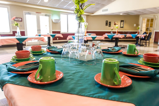 A beautifully arranged dining table ready for an event, featuring colorful tableware and a floral centerpiece.