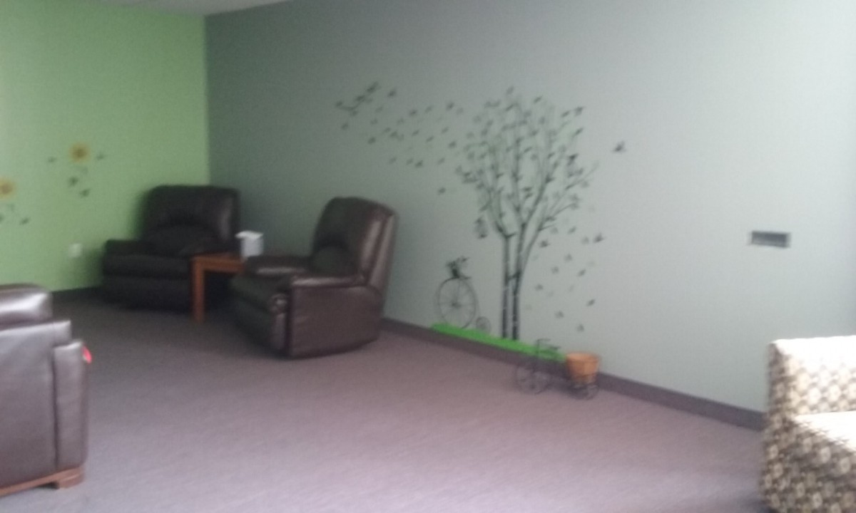 A cozy living room with leather chairs and a tree mural on the wall.