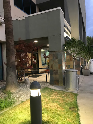 An entrance to a modern building, featuring landscaping and ambient lighting.