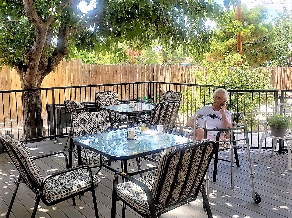 A peaceful outdoor patio with a person relaxing under the shade of trees.