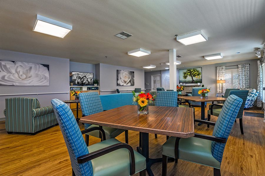 A neatly arranged dining area with wooden tables, comfortable chairs, and floral decorations.
