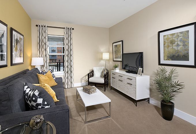 A modern, minimalist living room with neutral tones, featuring a comfortable sofa, armchair, and a sleek TV stand.