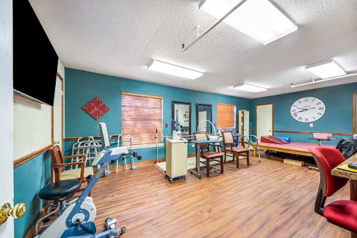 A spacious therapy room equipped with exercise equipment and a calming blue decor.