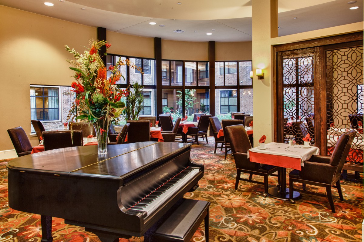 A cozy restaurant interior with a grand piano and elegant table settings.