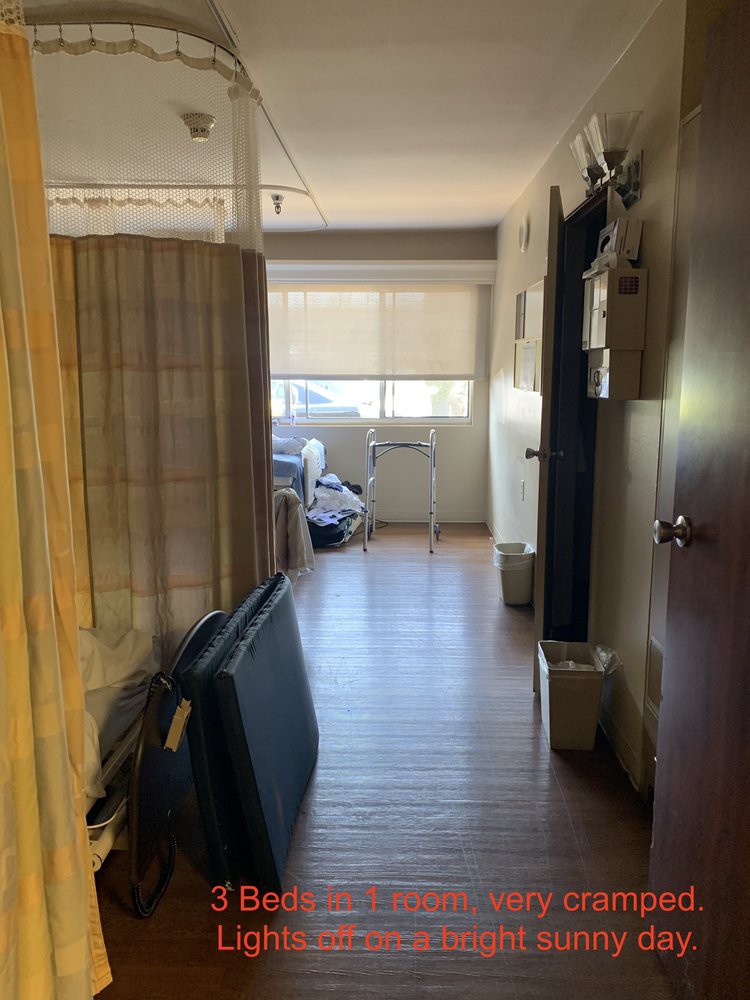 A hallway leading to a room with a large window and wooden flooring.