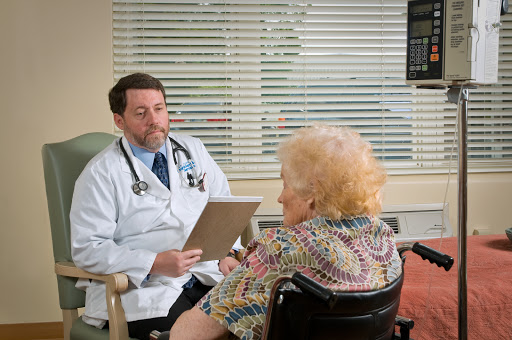 A doctor consults with an elderly patient in a healthcare setting.