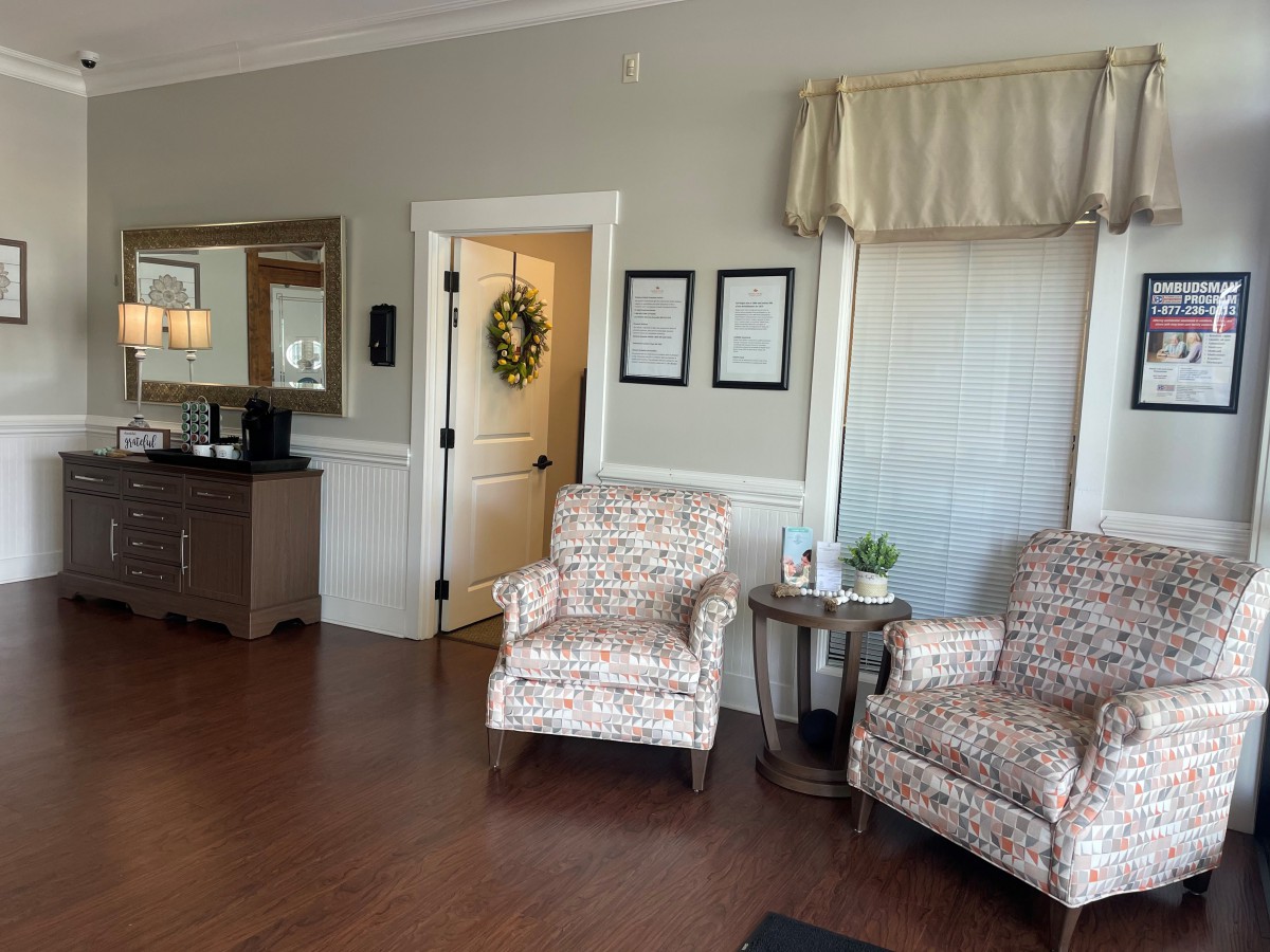 A cozy living room with patterned chairs, a side table, and a decorative wreath on the door.
