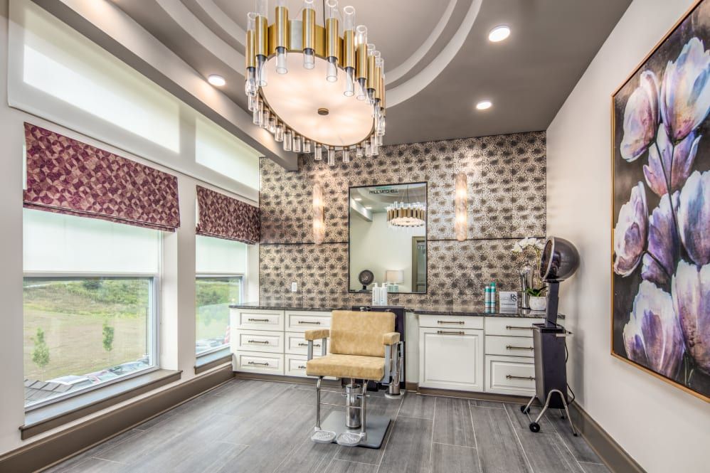 A luxurious salon interior featuring a stylish chandelier and barber chair.