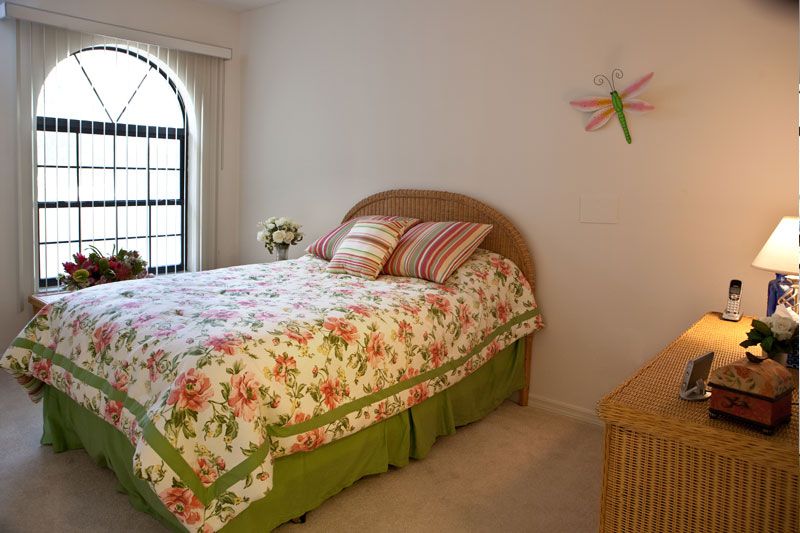 A cozy bedroom with floral bedding and a decorative dragonfly on the wall.