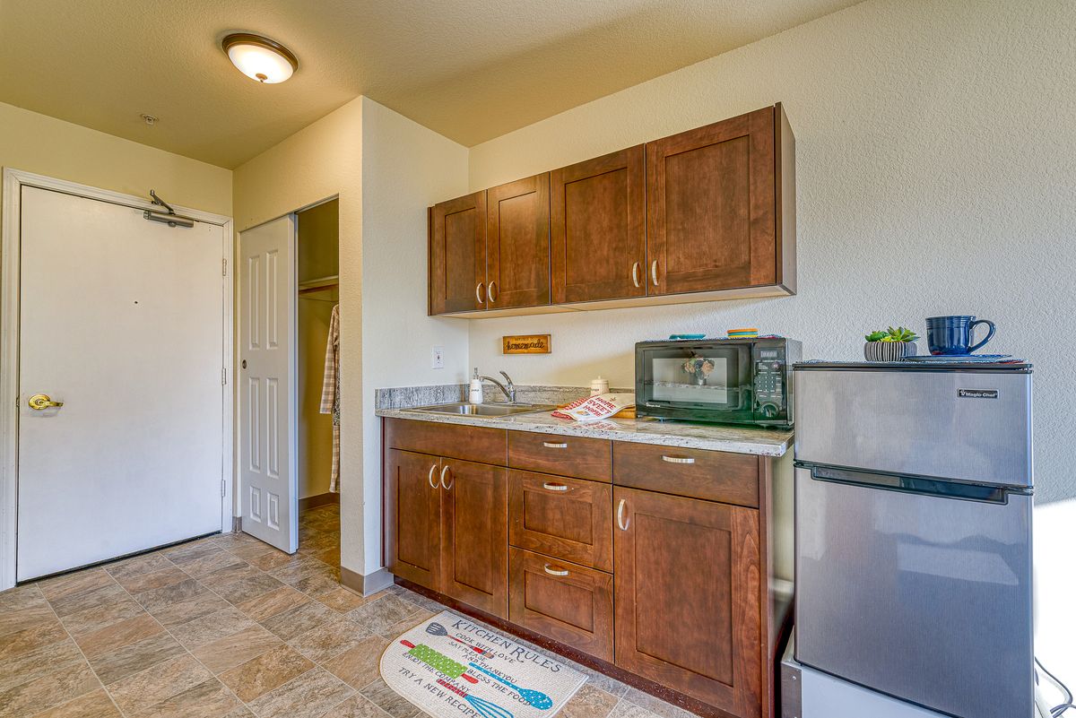 A small kitchen area with wooden cabinets, a refrigerator, and a microwave.
