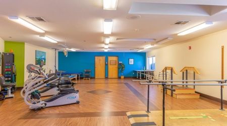 A spacious rehabilitation gym with exercise equipment and therapy tools.