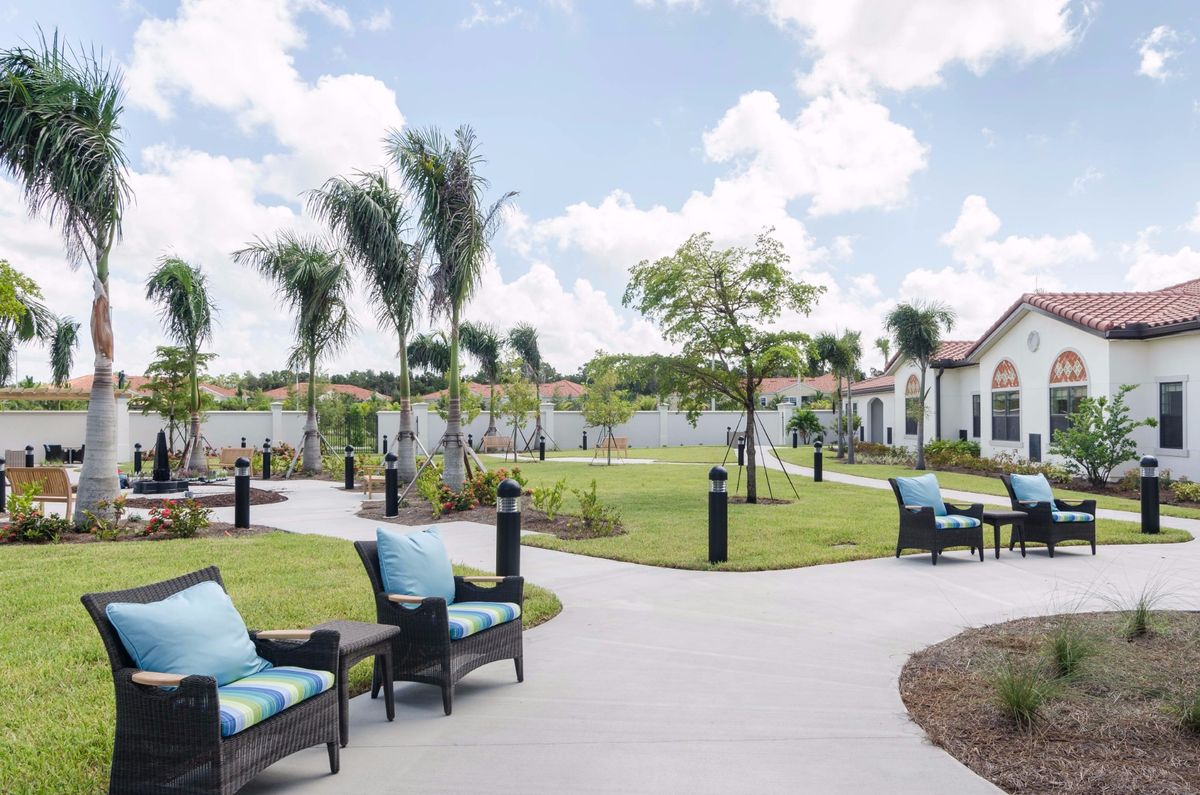 A serene outdoor garden with chairs and pathways under a partly cloudy sky.