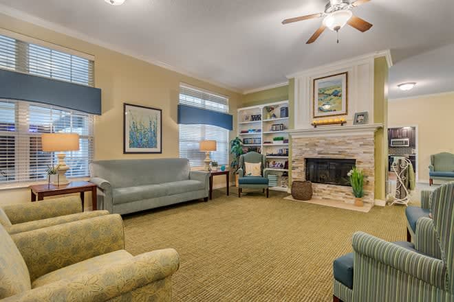 A cozy living room with a sofa, armchairs, a fireplace, and bookshelves.