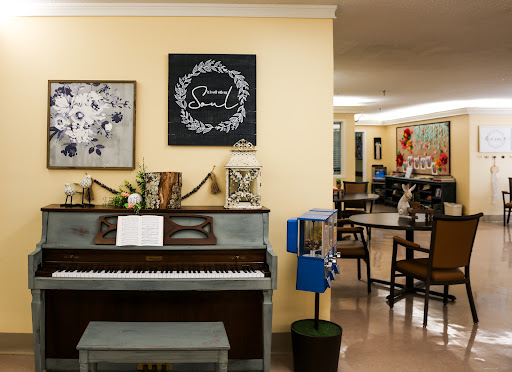A cozy community space featuring a piano, art on the walls, and seating arrangements for gatherings.