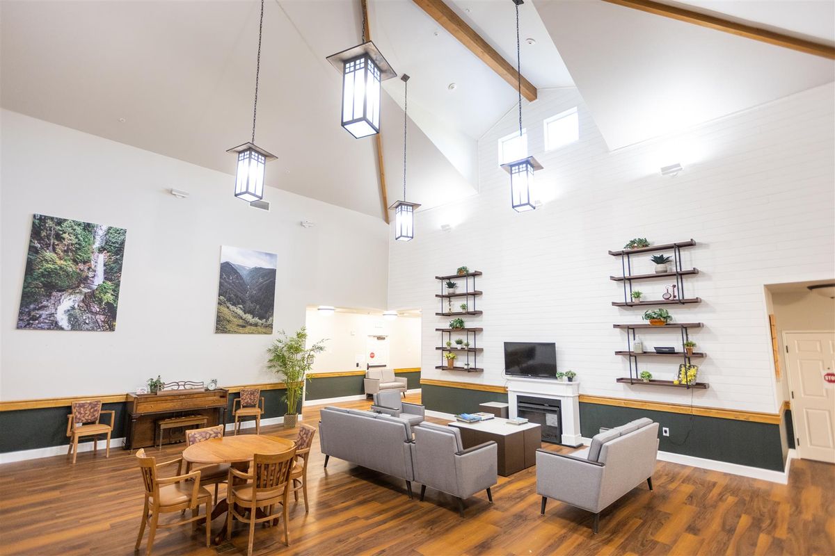 A modern living room with high ceilings, featuring a comfortable seating area, wooden floors, and stylish hanging lights.