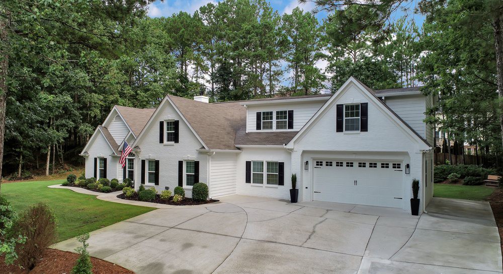 A suburban house with a spacious driveway and a well-maintained lawn.