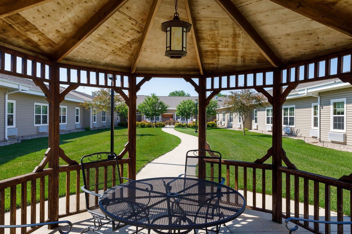 A scenic view from inside a gazebo, overlooking a landscaped garden and pathway.