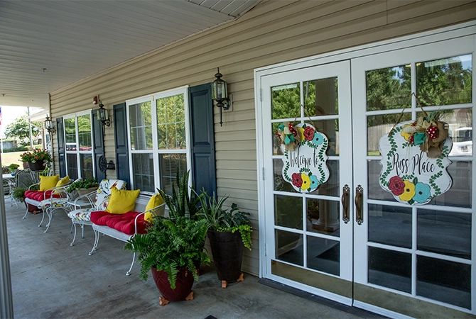 A cozy front porch with a bench, plants, and decorative glass doors.