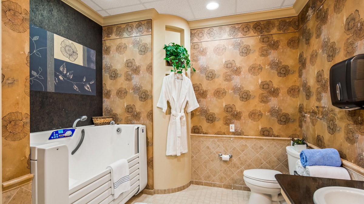 A luxurious bathroom with a walk-in bathtub, elegant wallpaper, and a hanging robe.