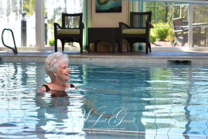 An elderly woman enjoying a relaxing swim in an indoor pool.