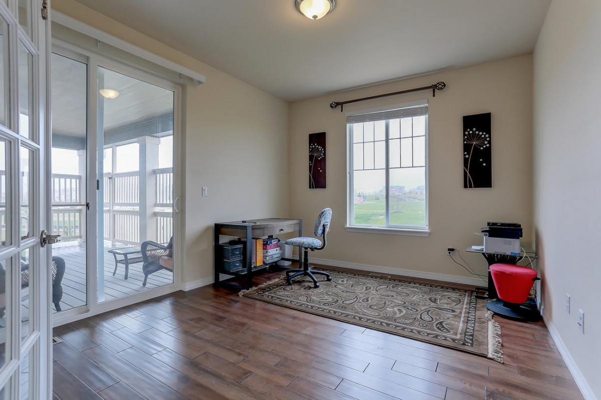 A well-lit home office with a desk and chair, featuring hardwood floors and decorative elements.