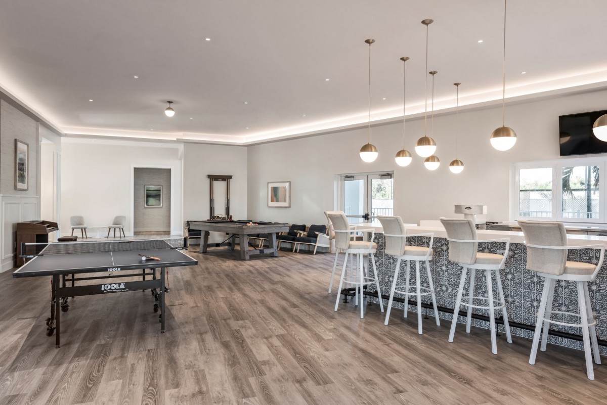 A modern open-concept room featuring a kitchen island with bar stools and stylish pendant lighting.