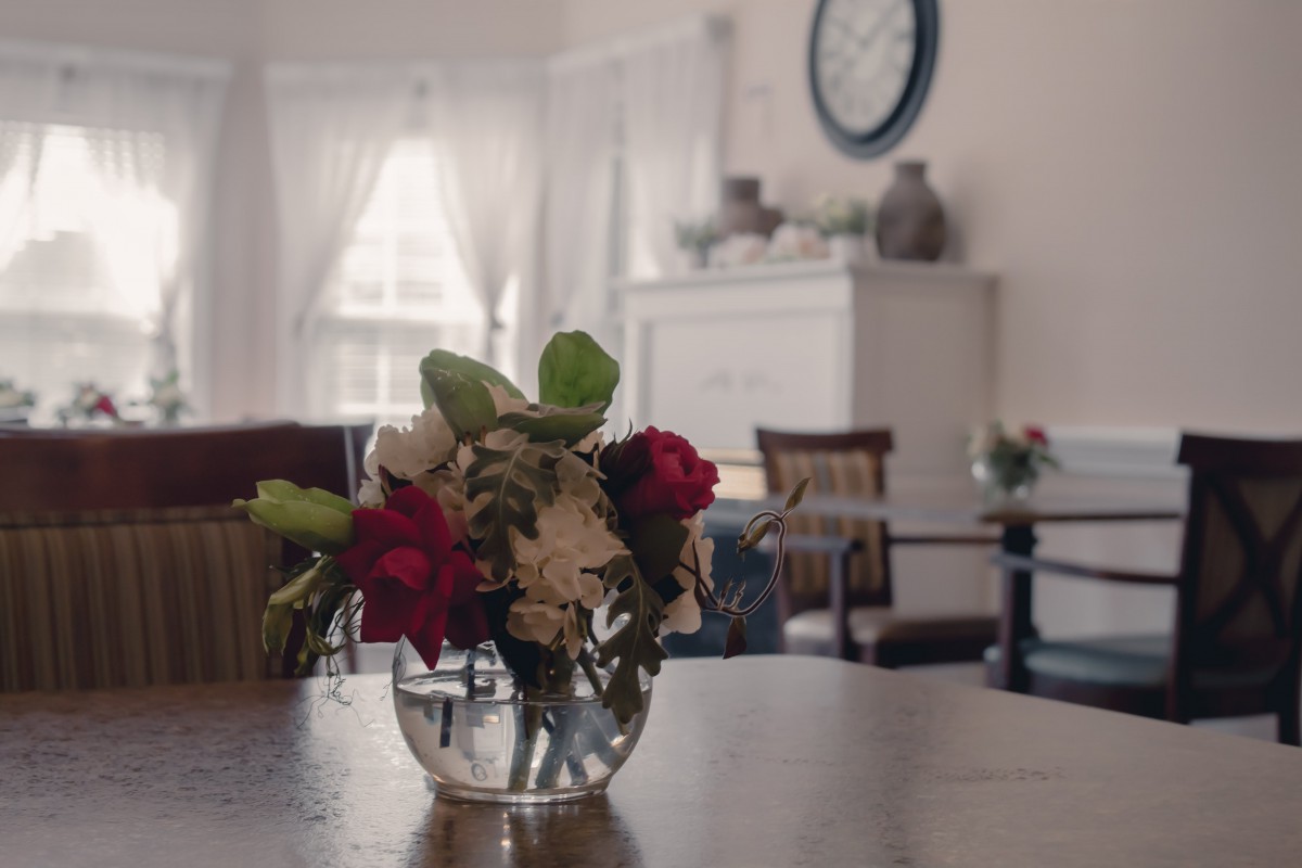 A cozy living room with a vase of flowers on a wooden table, illuminated by natural light.