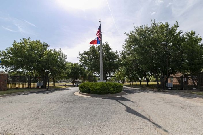 A flag is displayed on a pole in the center of a roundabout surrounded by trees.