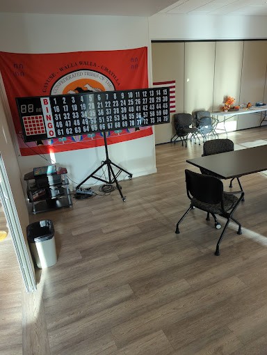 An empty classroom with tables, chairs, and a flag on the wall.