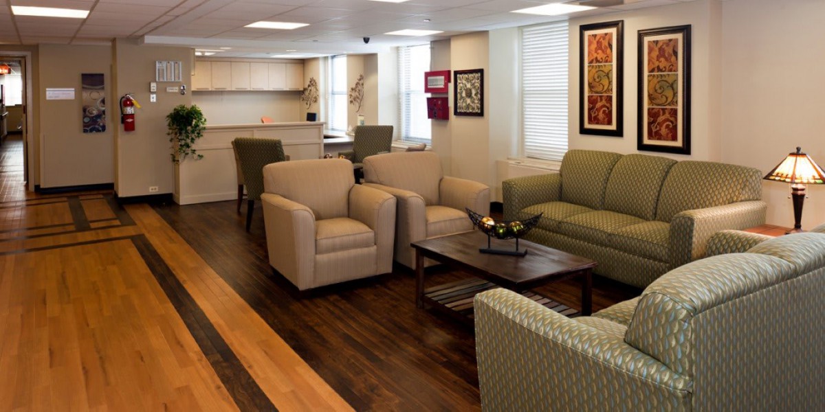 A comfortable lounge area with sofas, chairs, and a coffee table, featuring wooden flooring and artwork on the walls.