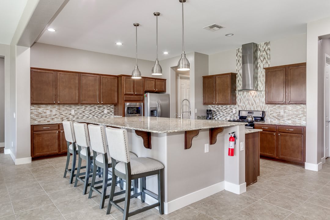 A modern kitchen with a large island, bar stools, and stylish pendant lighting.