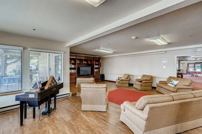 A spacious living room featuring a piano, comfortable seating, and a television.
