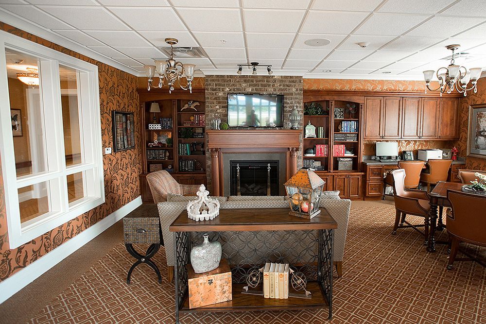 A cozy living room with wooden furniture and a fireplace, featuring bookshelves and decorative items.