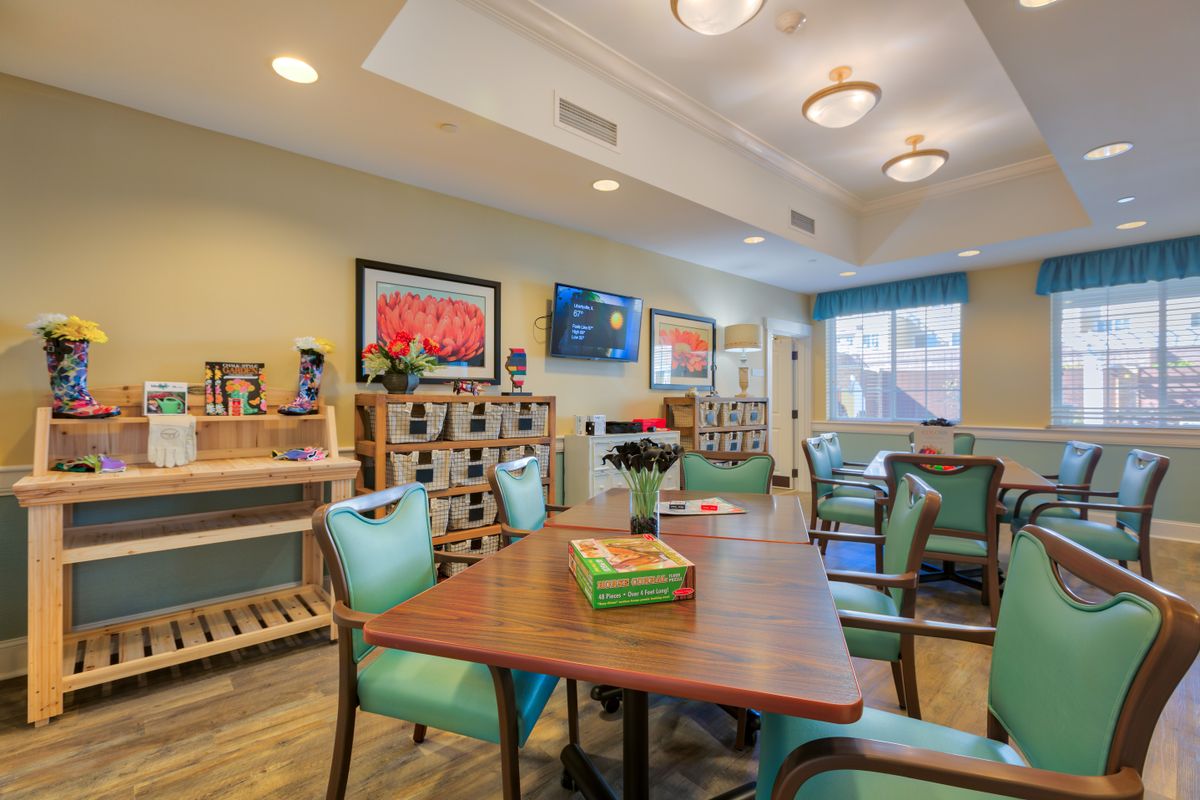 A cozy living room with a television, decorated with artwork and comfortable seating.