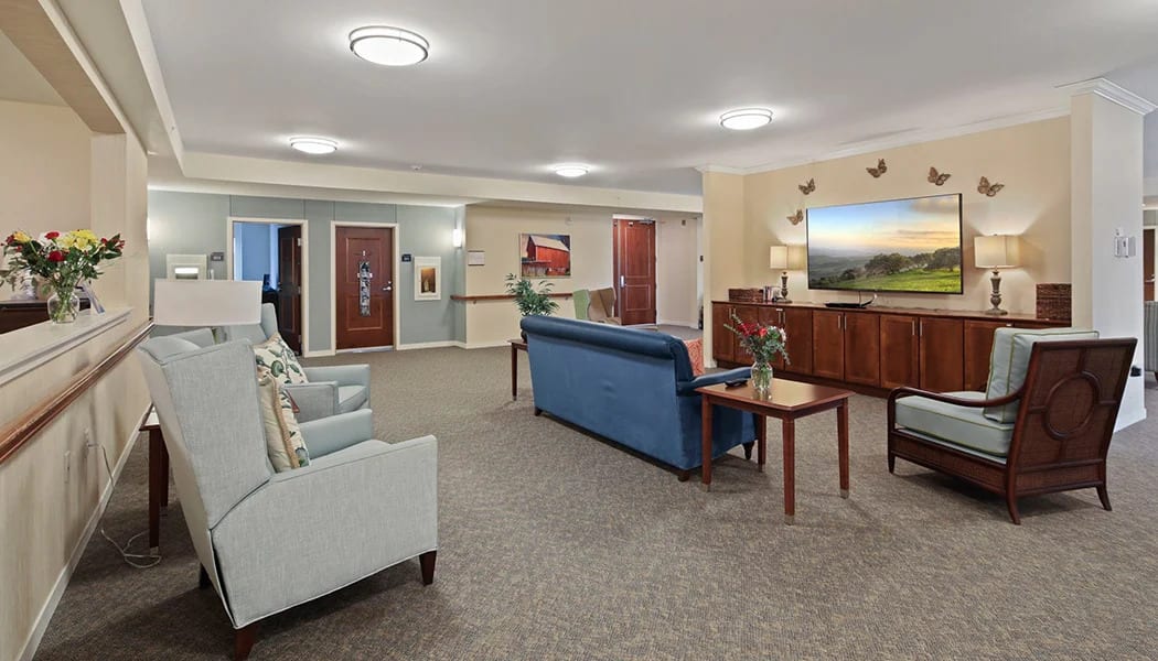 A spacious living room with comfortable seating, artwork on the walls, and ambient lighting.