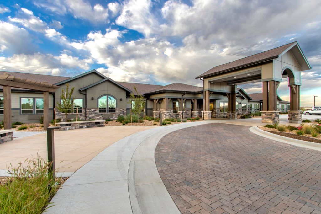 A modern building with a curved driveway under a cloudy sky.