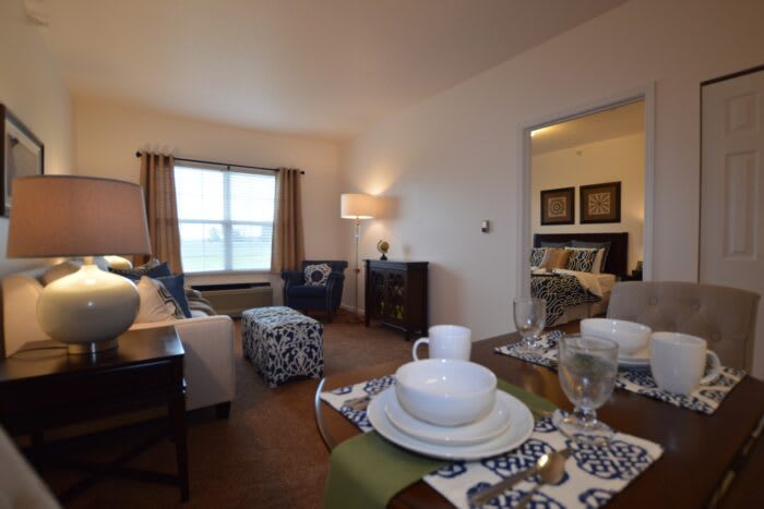 A cozy living room with a dining area, featuring comfortable seating and a neatly set table.